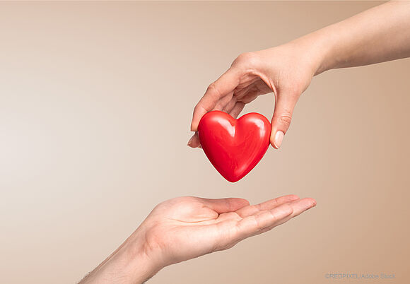 Eine Hand gibt ein Herz in eine anderen Hand | Darstellung zu einer Weihnachsspende | Fondsdepotbank